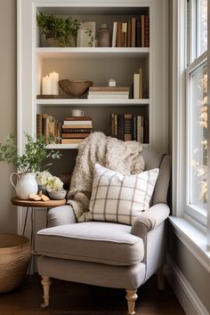 a white chair sitting in front of a window next to a shelf filled with books