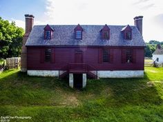 an old red house sitting on top of a lush green field