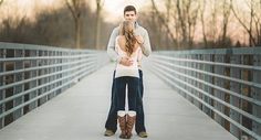 a man and woman standing on a bridge with their arms around each other's backs