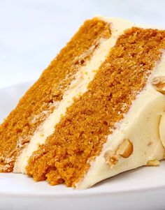 a slice of carrot cake with white frosting and walnuts on a white plate