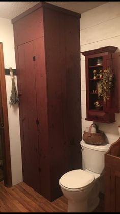 a white toilet sitting next to a wooden cabinet