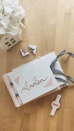 an open book with ribbon on the floor next to flowers and other items that are laying around it