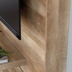 a flat screen tv mounted to the side of a wooden wall next to a book shelf