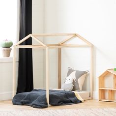 a wooden doll house sitting on top of a rug next to a window with curtains