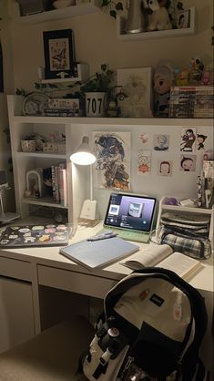 a laptop computer sitting on top of a desk next to a lamp and other items