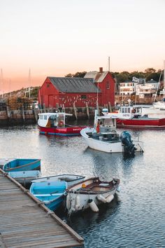 several boats are docked in the water near a red building with a red roof on it