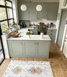 a kitchen with green cabinets and white counter tops, an area rug on the floor