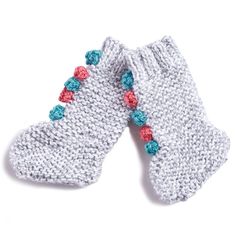 two white knitted mittens with colorful flowers on the top and bottom, sitting next to each other