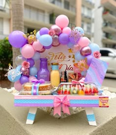 a table topped with lots of balloons and confetti on top of a sidewalk