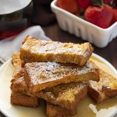 french toast on a plate with powdered sugar and strawberries in the back ground