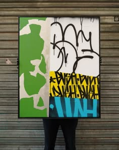 a man holding up a large piece of art with graffiti on it's side