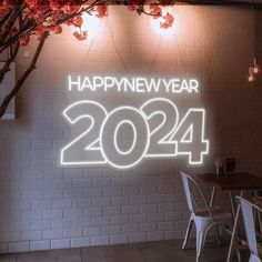 the happy new year sign is lit up in front of a brick wall and table