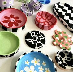 many different colored plates and bowls on a table with flowers painted on the lids,