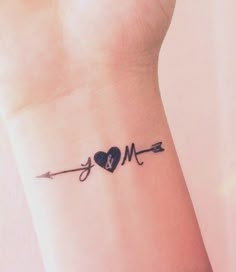 a small wrist tattoo with an arrow, heart and bow on the left side of it