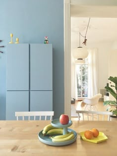 a wooden table topped with fruit on top of it next to a blue refrigerator freezer