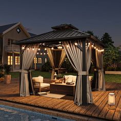 a gazebo sitting on top of a wooden deck next to a swimming pool at night