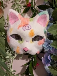 a close up of a cat mask with flowers in the background