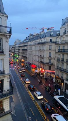 a city street filled with lots of traffic next to tall buildings and cars driving down the road