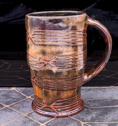 a brown and black mug sitting on top of a tile floor