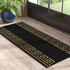 a black and gold area rug in front of a door with a potted plant