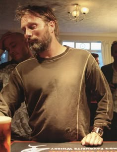 a man standing in front of a table with a glass of beer on top of it