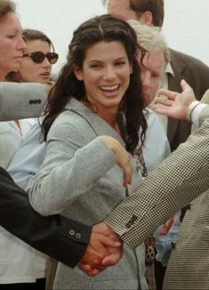 a man and woman shaking hands in front of other people