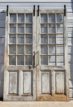 an old double door with glass panes on the outside and inside, in front of a house