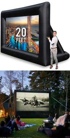 an inflatable movie screen with a man standing next to it and people sitting on the grass