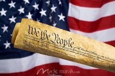 we the people written on a piece of parchment paper in front of an american flag