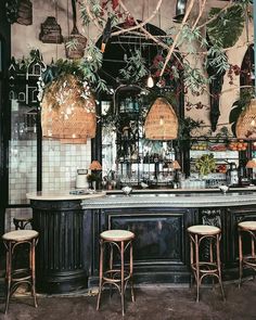 the bar is decorated with plants and wicker hanging from it's ceiling, along with stools