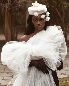 a woman wearing a white dress and veil with flowers on her head, is posing for the camera