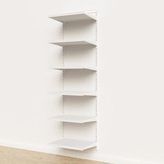 an empty white shelf in the corner of a room next to a wooden floor and wall