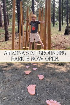 a young boy standing on top of a wooden structure with pink footprints in the dirt