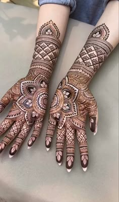 two hands with henna tattoos on them, one is showing it's intricate designs