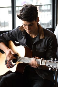 a young man is playing an acoustic guitar