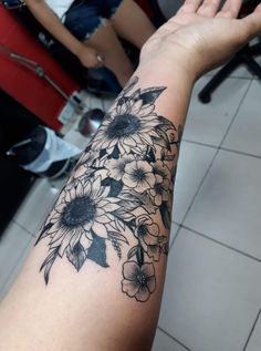 a woman's arm with black and white flowers on the inside of her arm