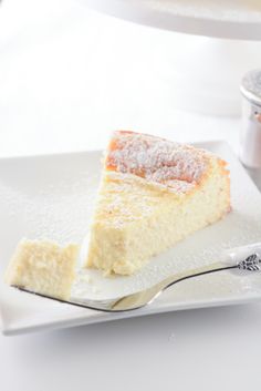 a piece of cake on a white plate with a silver serving spoon next to it