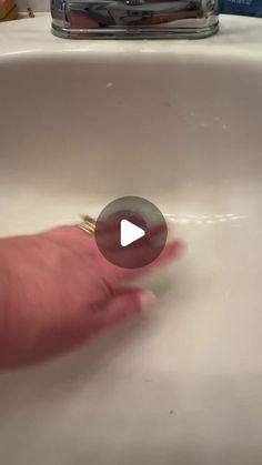 a person's hand reaching into a sink with water in the faucet