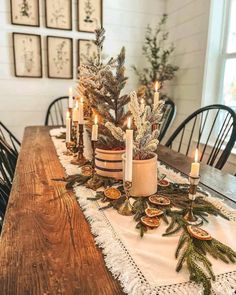 a wooden table topped with lots of candles and greenery next to a potted plant