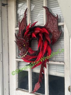 a red dragon wreath hanging on the side of a white door in front of a window