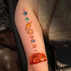 the solar system tattoo on the arm is shown with planets and sun in different colors