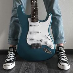 a black and white photo of a person sitting with an electric guitar in their lap