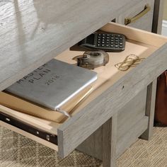 an open drawer with a book, cell phone and wallet on it next to a purse