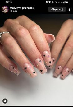 a woman's hands with pink and black hearts on them, holding onto her nails