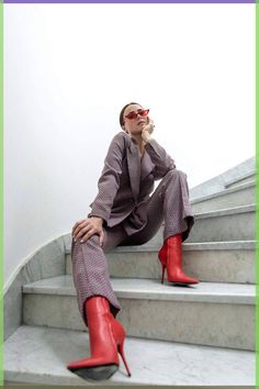 a woman sitting on the steps talking on her cell phone and wearing red high heels