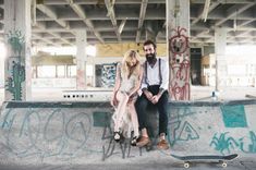 a man and woman sitting next to each other on a skateboard in an abandoned building