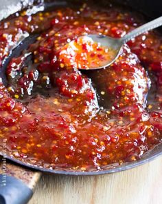 a skillet filled with sauce on top of a wooden table