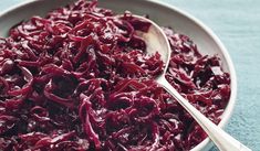 a bowl filled with red cabbage next to a spoon