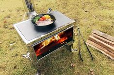 a stove that has some food on top of it in the grass next to a wooden pallet