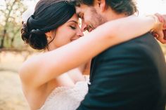 a bride and groom embracing each other in the woods